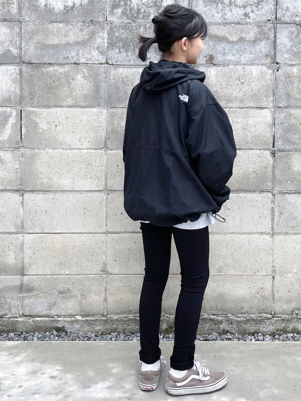 ブラック系のナイロンジャケット、ブラック系のチノパンツ、ベージュ系のスニーカーを着用したキッズの秋コーディネートの2枚目の写真