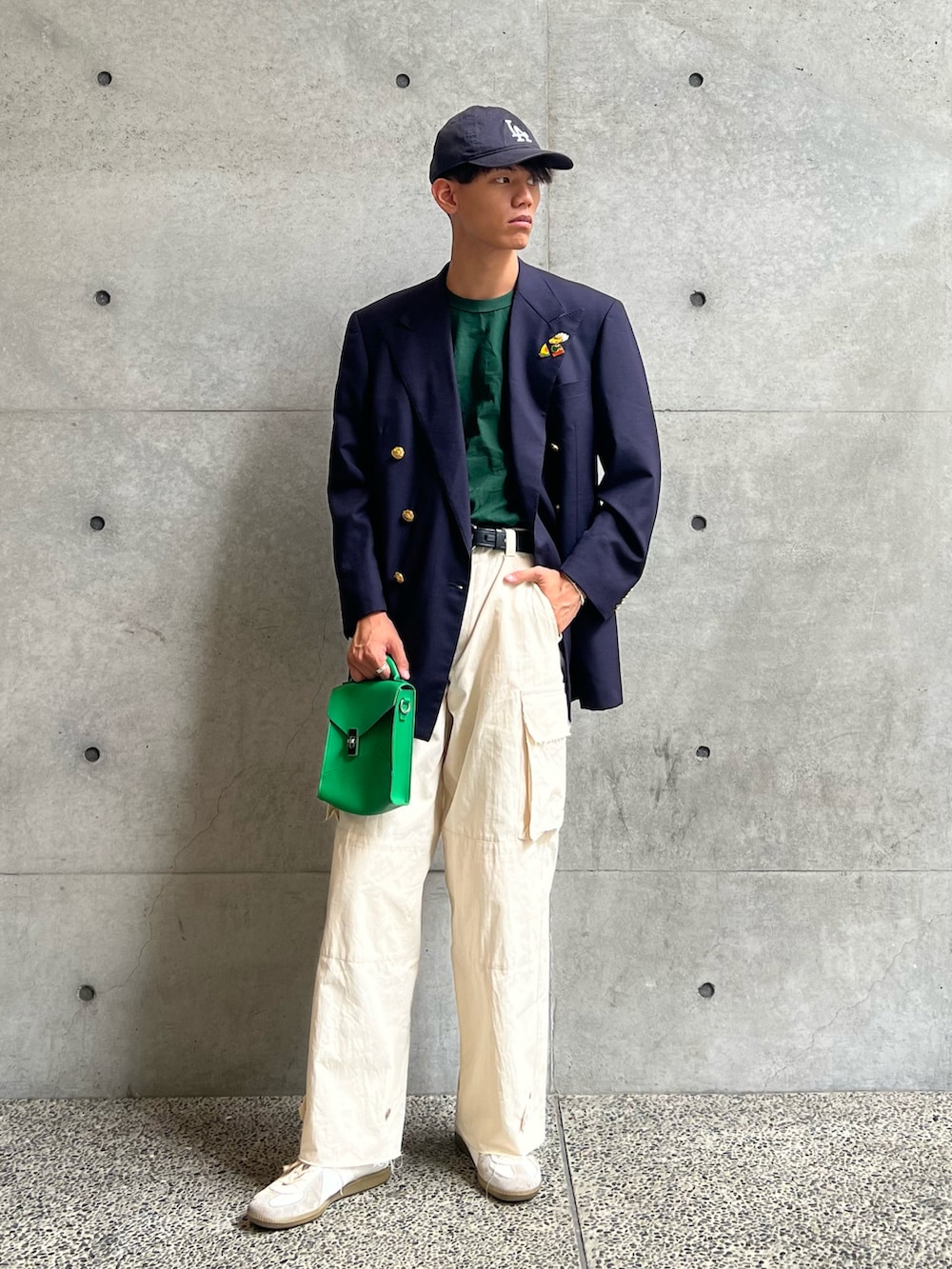 グリーン系のTシャツ/カットソー、グリーン系のショルダーバッグ、ホワイト系のカーゴパンツを着用したメンズの秋コーディネートの2枚目の写真