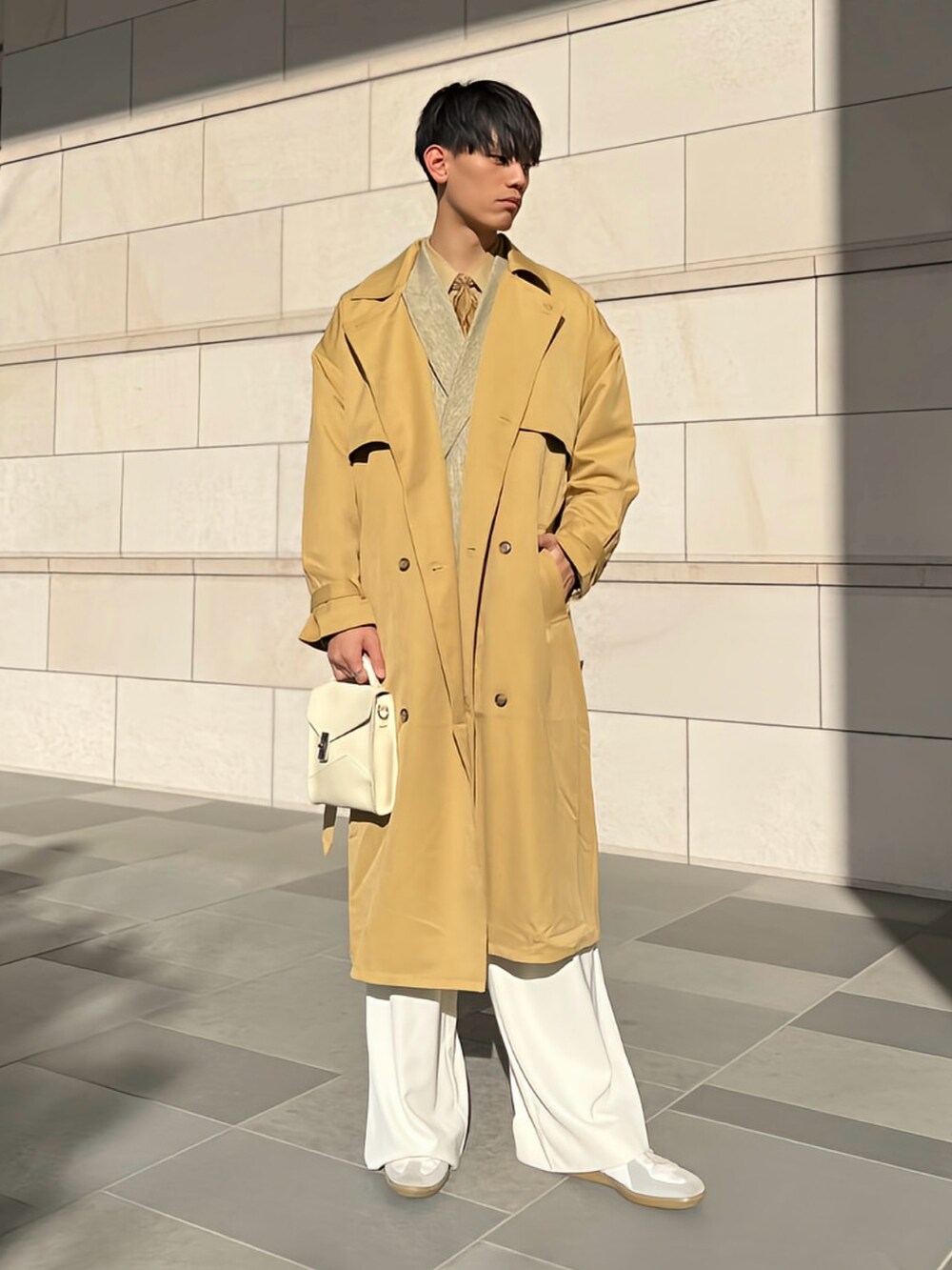 ベージュ系のトレンチコート、イエロー系のテーラードジャケット、ホワイト系のショルダーバッグを着用したメンズの春コーディネートの2枚目の写真