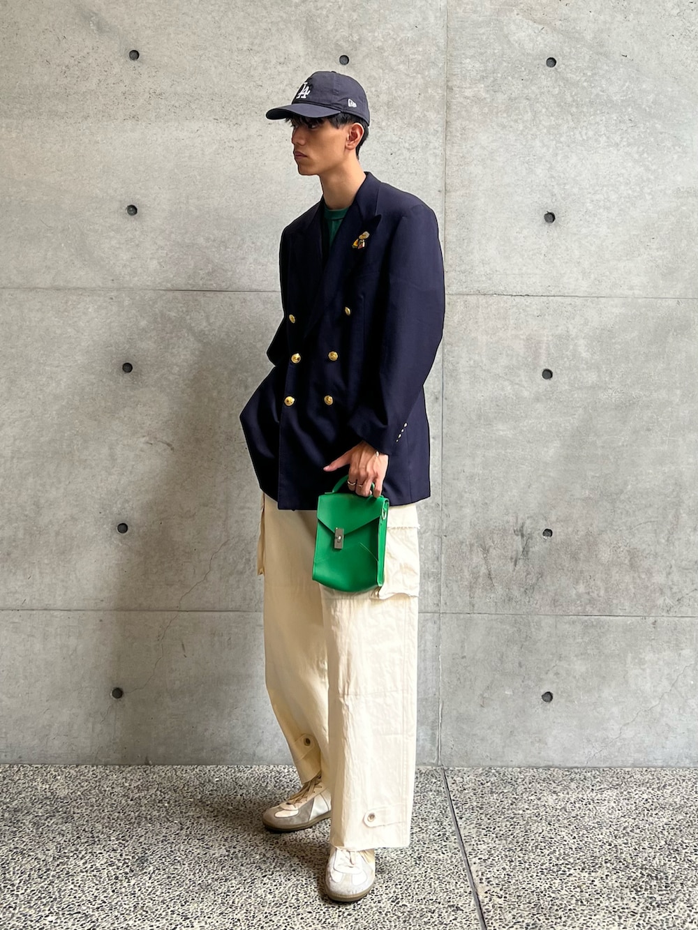 グリーン系のTシャツ/カットソー、グリーン系のショルダーバッグ、ホワイト系のカーゴパンツを着用したメンズの秋コーディネートの3枚目の写真