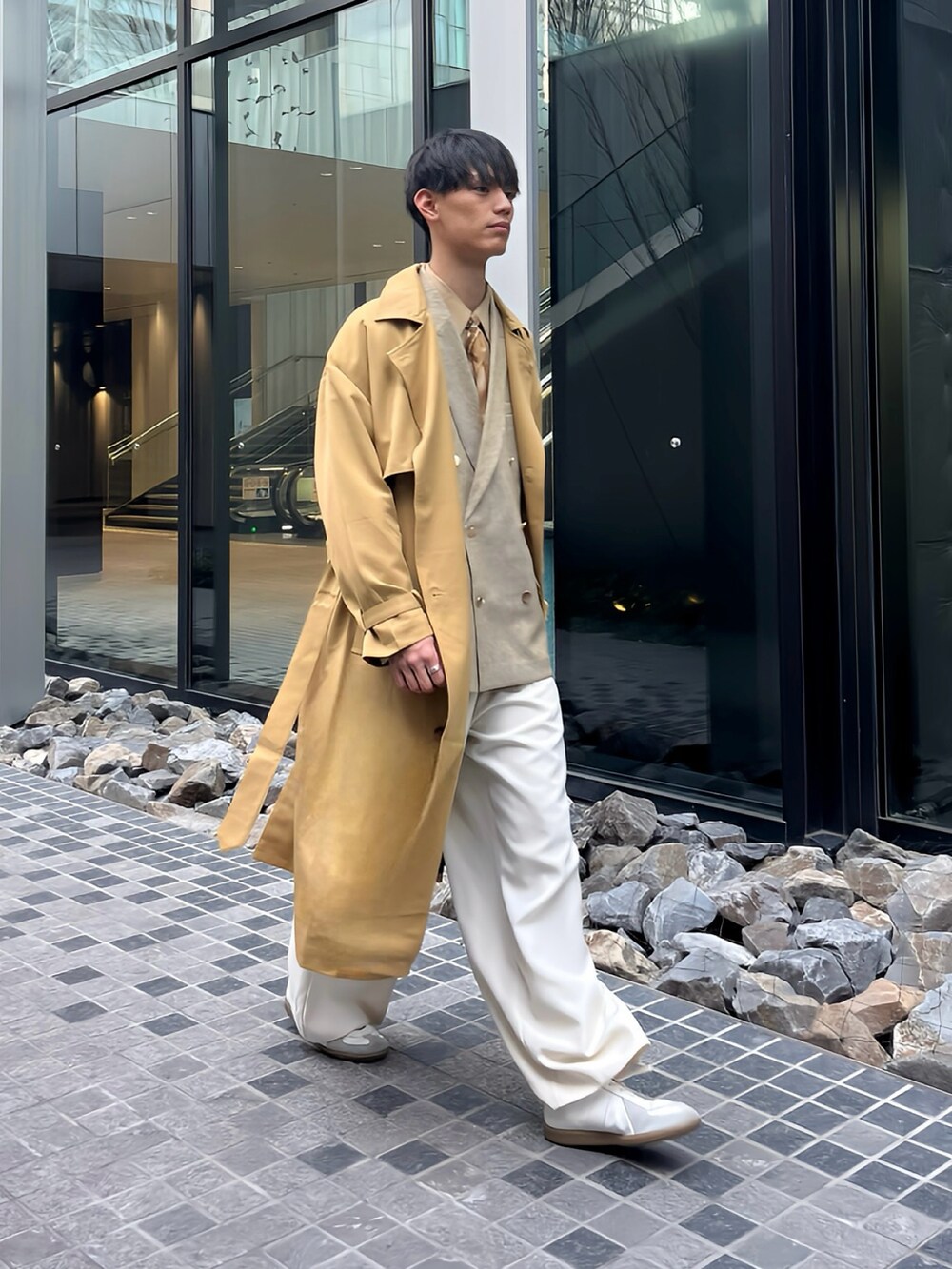 ベージュ系のトレンチコート、イエロー系のテーラードジャケット、ホワイト系のショルダーバッグを着用したメンズの春コーディネートの3枚目の写真