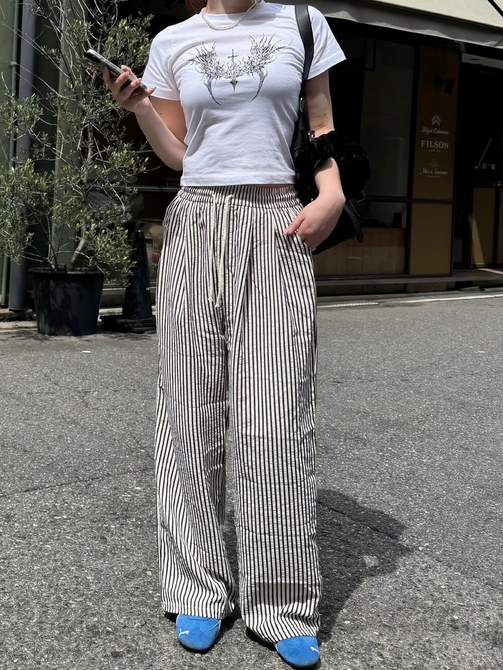 ブラック系のその他パンツ、ホワイト系のTシャツ/カットソー、ブラック系のショルダーバッグを着用したレディースの春コーディネートの2枚目の写真