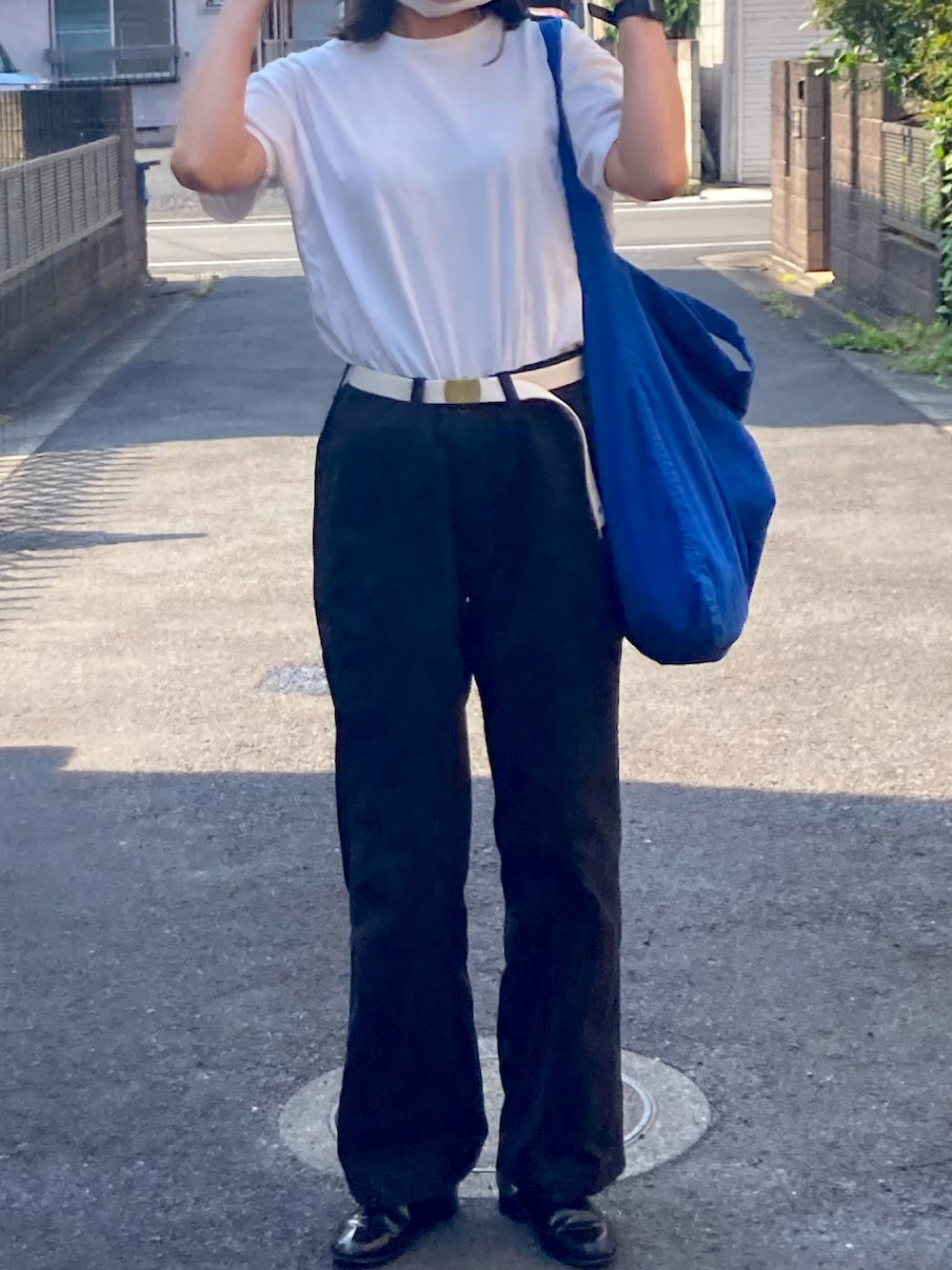 ブラック系のチノパンツ、ホワイト系のTシャツ/カットソー、ブルー系のトートバッグを着用したレディースの夏コーディネートの2枚目の写真