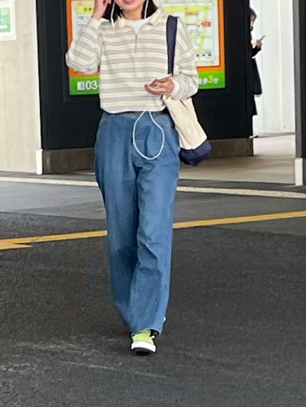 ブルー系のデニムパンツ、イエロー系のスニーカー、イエロー系のポロシャツを着用したレディースの春コーディネートの2枚目の写真