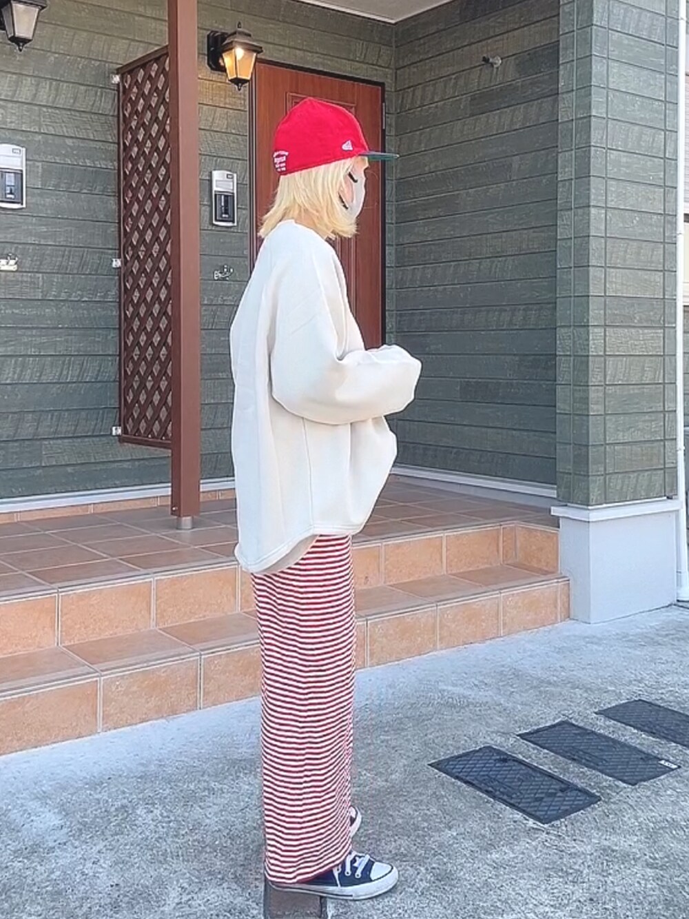 ベージュ系のスウェット、レッド系のスカート、ブラック系のスニーカーを着用したレディースの冬コーディネートの2枚目の写真