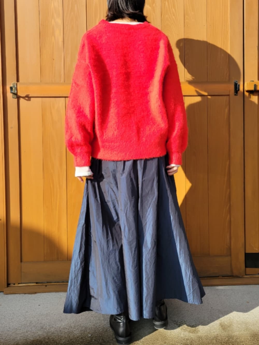 レッド系のニット/セーター、ホワイト系のニット/セーター、ブラック系のブーツを着用したレディースの秋コーディネートの3枚目の写真