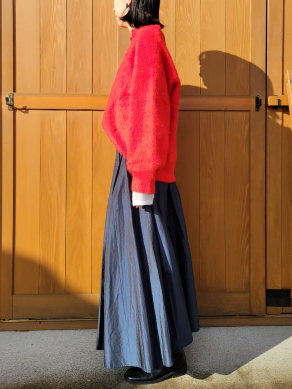 レッド系のニット/セーター、ホワイト系のニット/セーター、ブラック系のブーツを着用したレディースの秋コーディネートの2枚目の写真