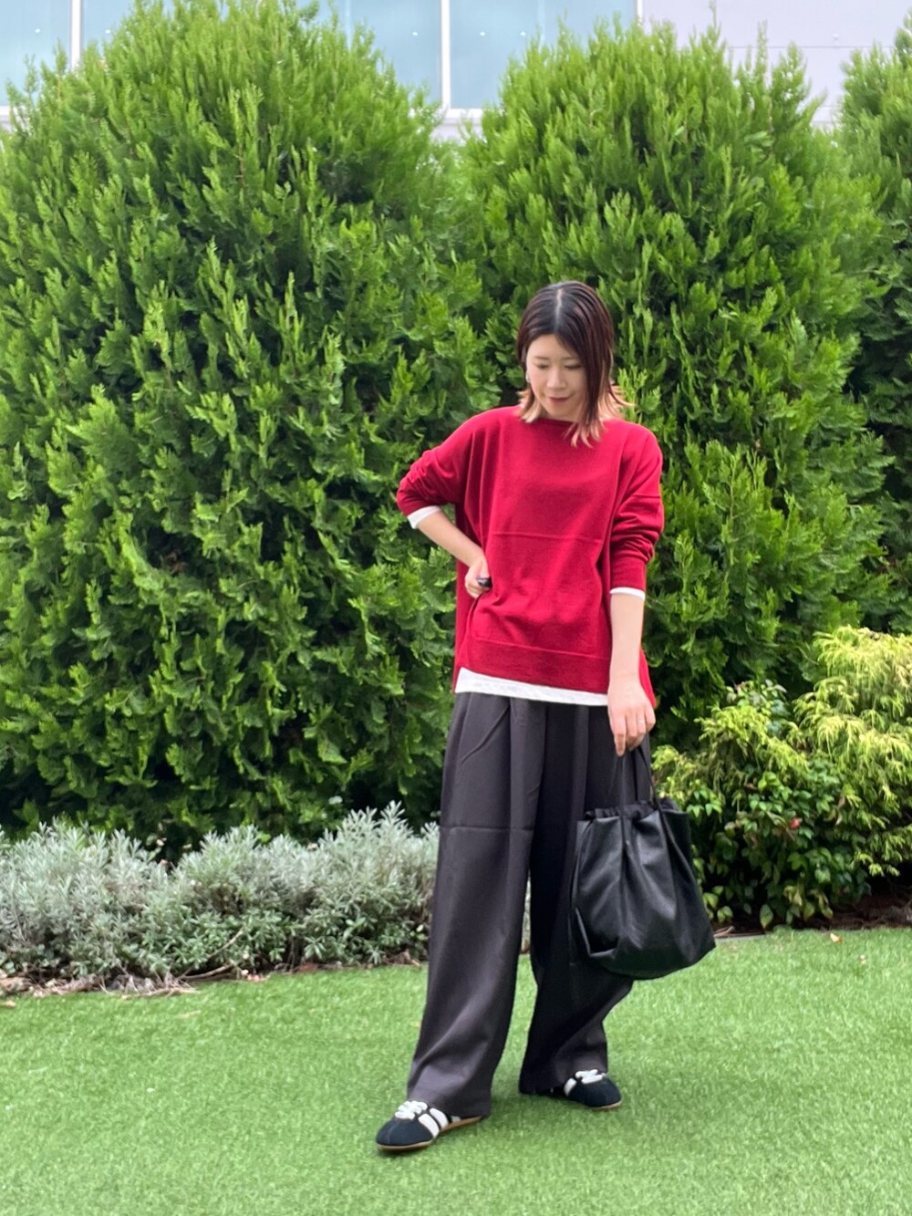 レッド系のニット/セーター、ホワイト系のTシャツ/カットソー、ブラック系のスニーカーを着用したレディースの秋コーディネートの2枚目の写真