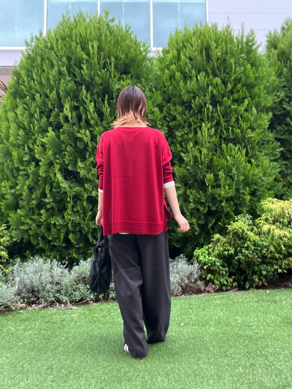 レッド系のニット/セーター、ホワイト系のTシャツ/カットソー、ブラック系のスニーカーを着用したレディースの秋コーディネートの4枚目の写真