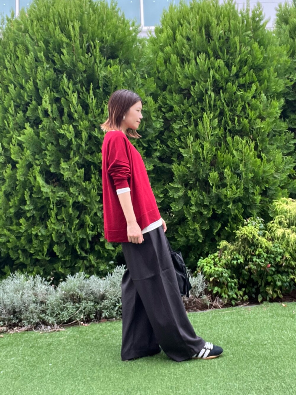 レッド系のニット/セーター、ホワイト系のTシャツ/カットソー、ブラック系のスニーカーを着用したレディースの秋コーディネートの3枚目の写真