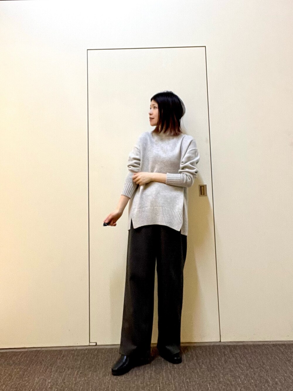 グリーン系のニット/セーター、グレー系のその他パンツ、ブラック系のブーツを着用したレディースの冬コーディネートの5枚目の写真