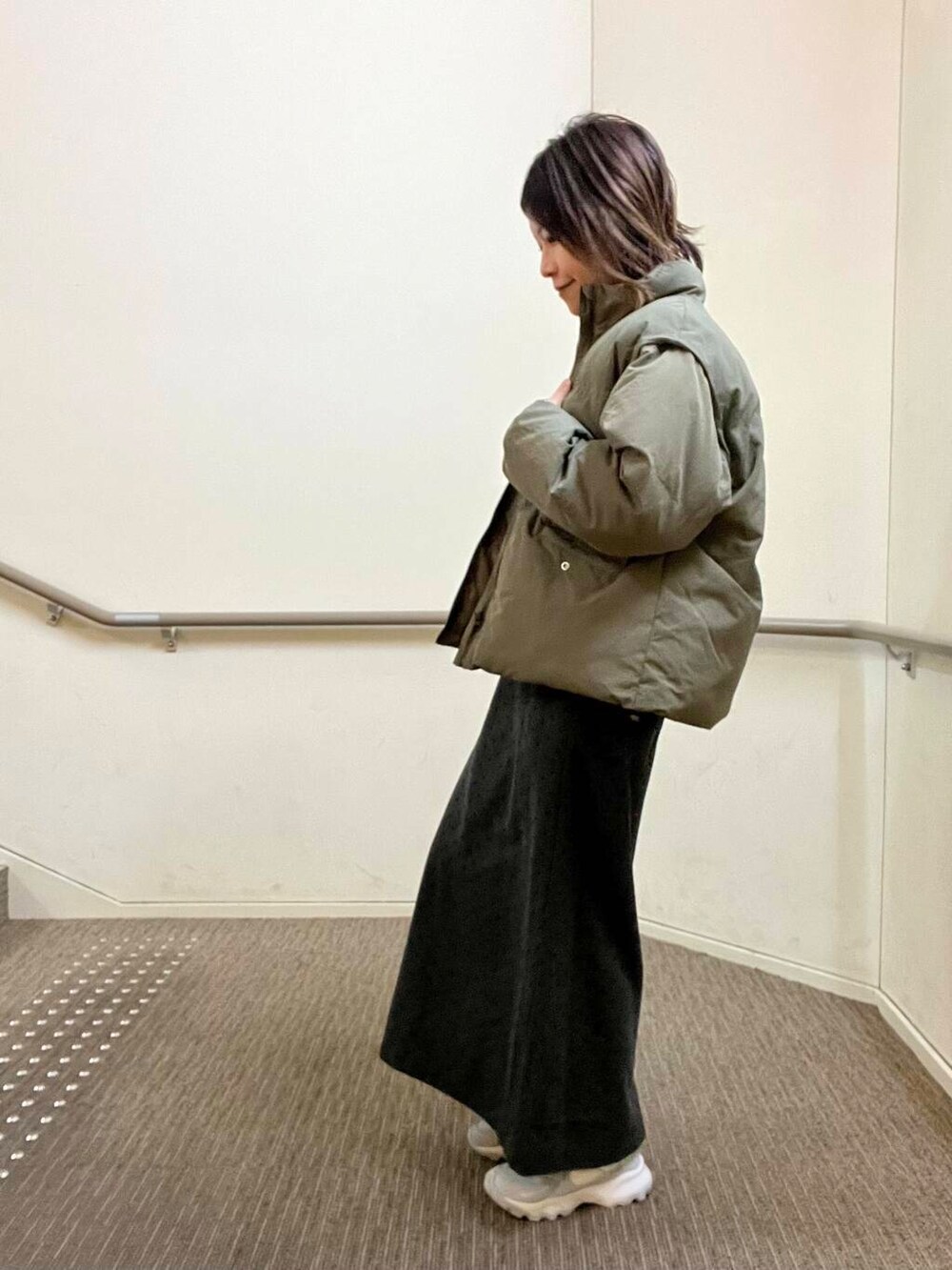 グレー系のスニーカー、グレー系のニット/セーター、グレー系のスカートを着用したレディースの冬コーディネートの2枚目の写真