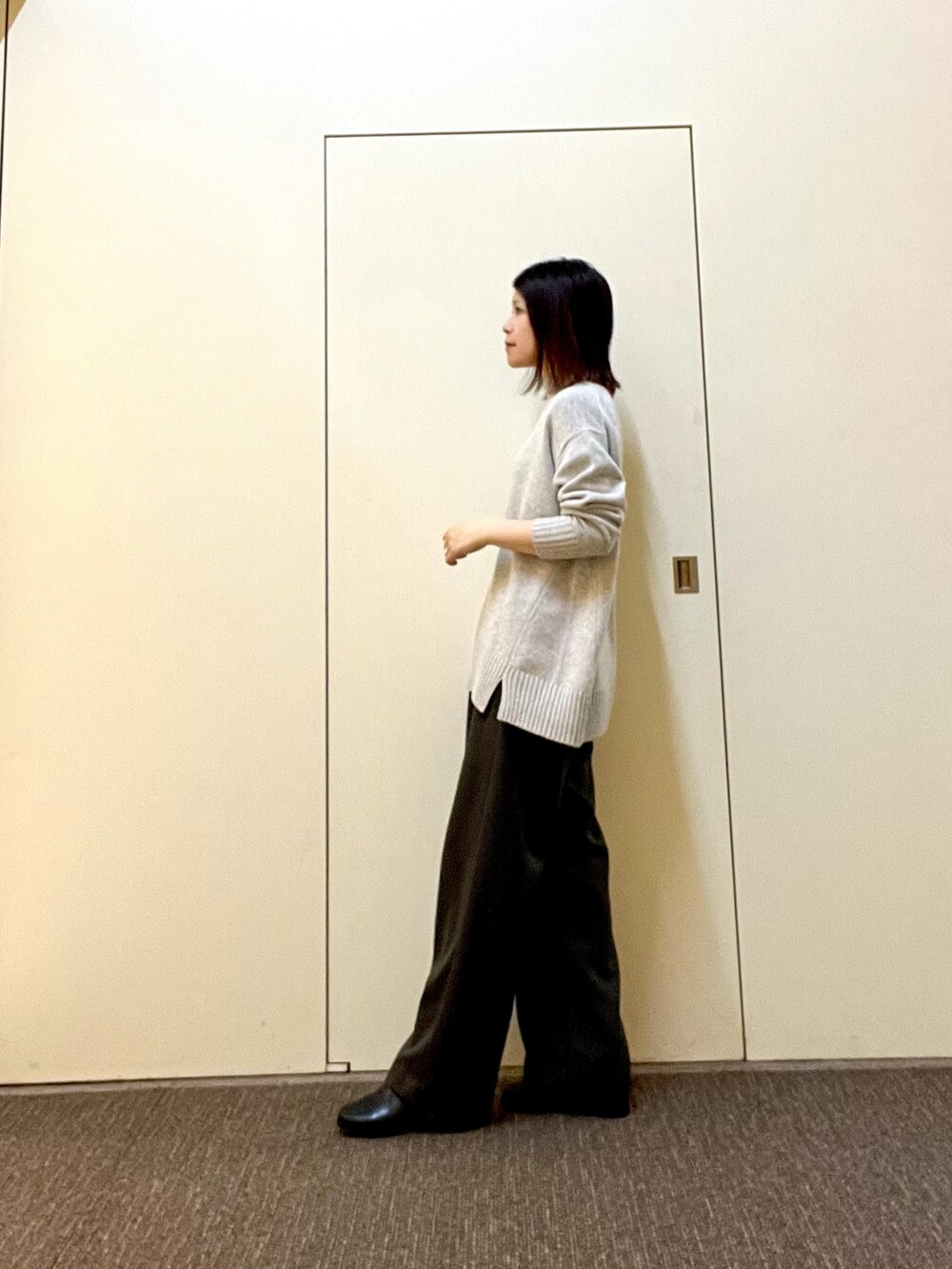 グリーン系のニット/セーター、グレー系のその他パンツ、ブラック系のブーツを着用したレディースの冬コーディネートの3枚目の写真