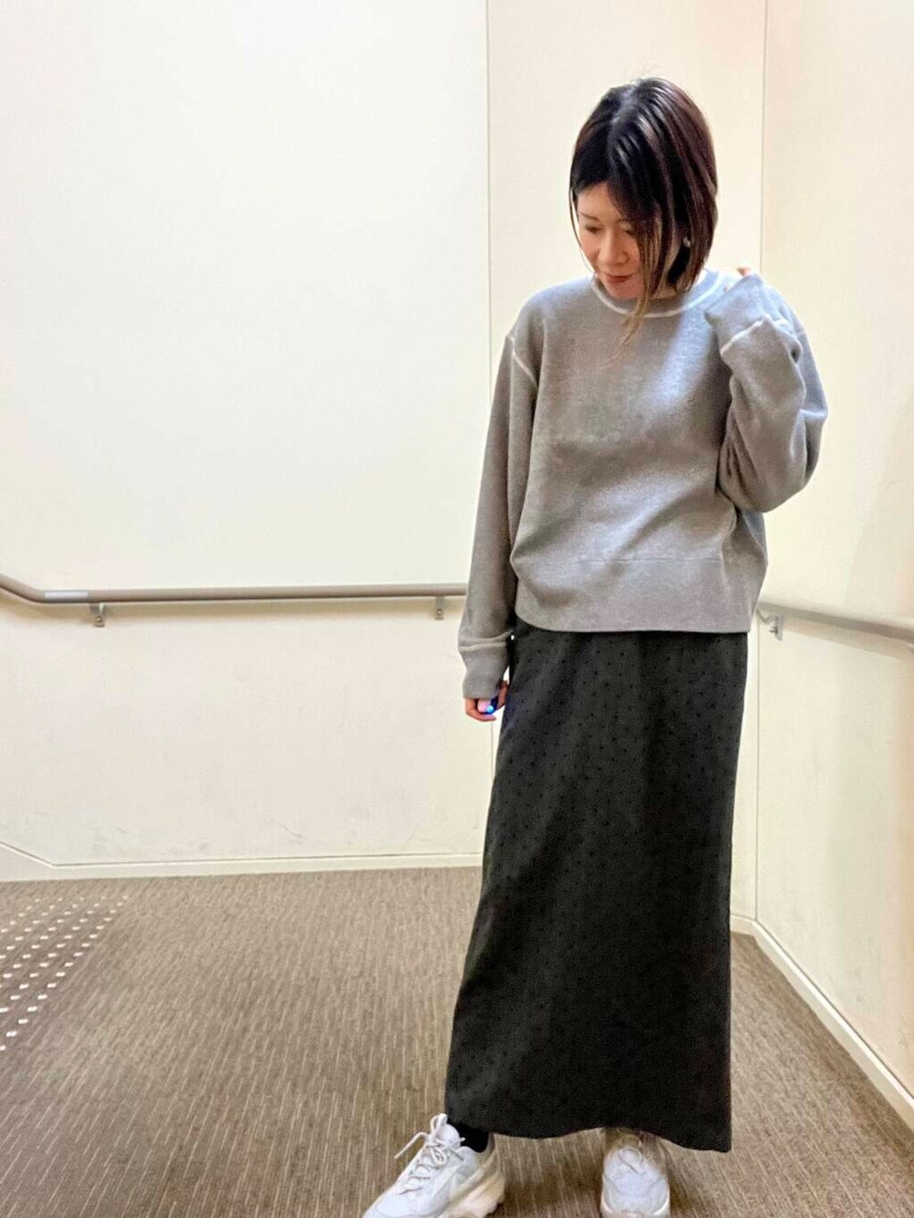 グレー系のスニーカー、グレー系のニット/セーター、グレー系のスカートを着用したレディースの冬コーディネートの5枚目の写真