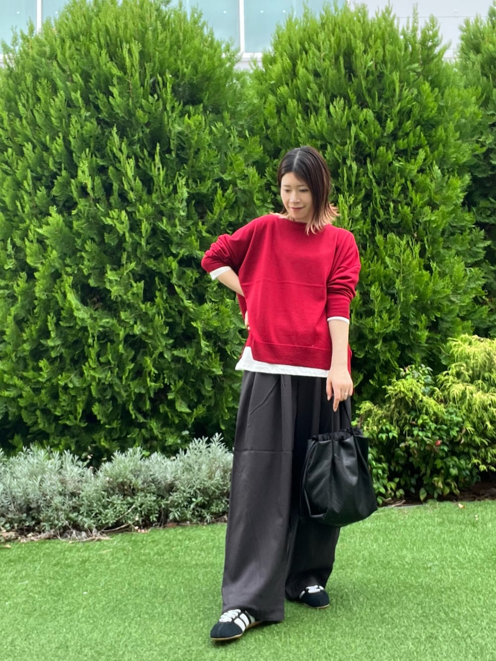 レッド系のニット/セーター、ホワイト系のTシャツ/カットソー、ブラック系のスニーカーを着用したレディースの秋コーディネートの6枚目の写真