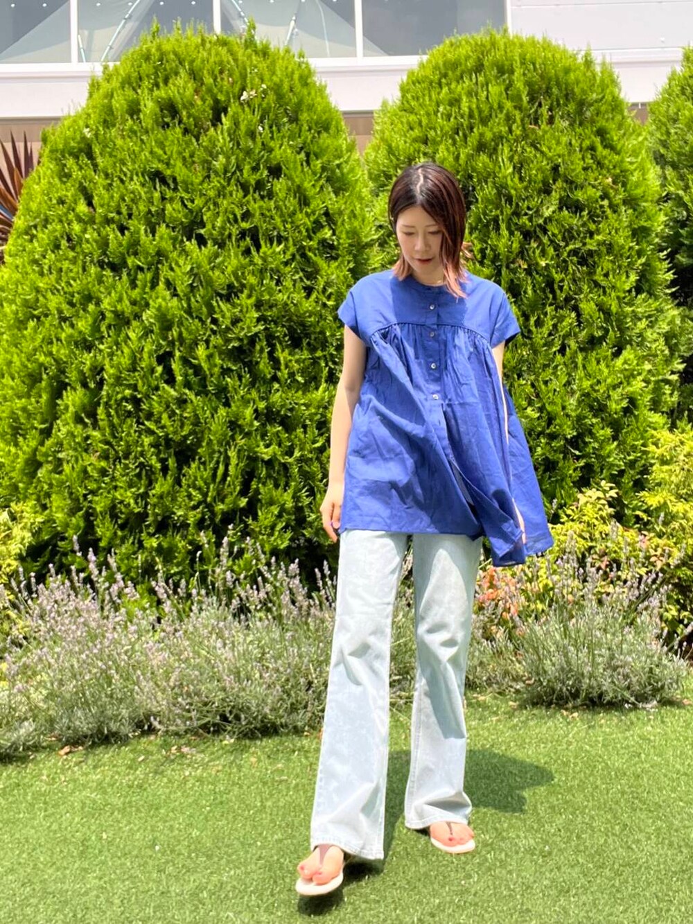 ブルー系のデニムパンツ、イエロー系のトートバッグ、ブラウン系のサンダルを着用したレディースの夏コーディネートの2枚目の写真