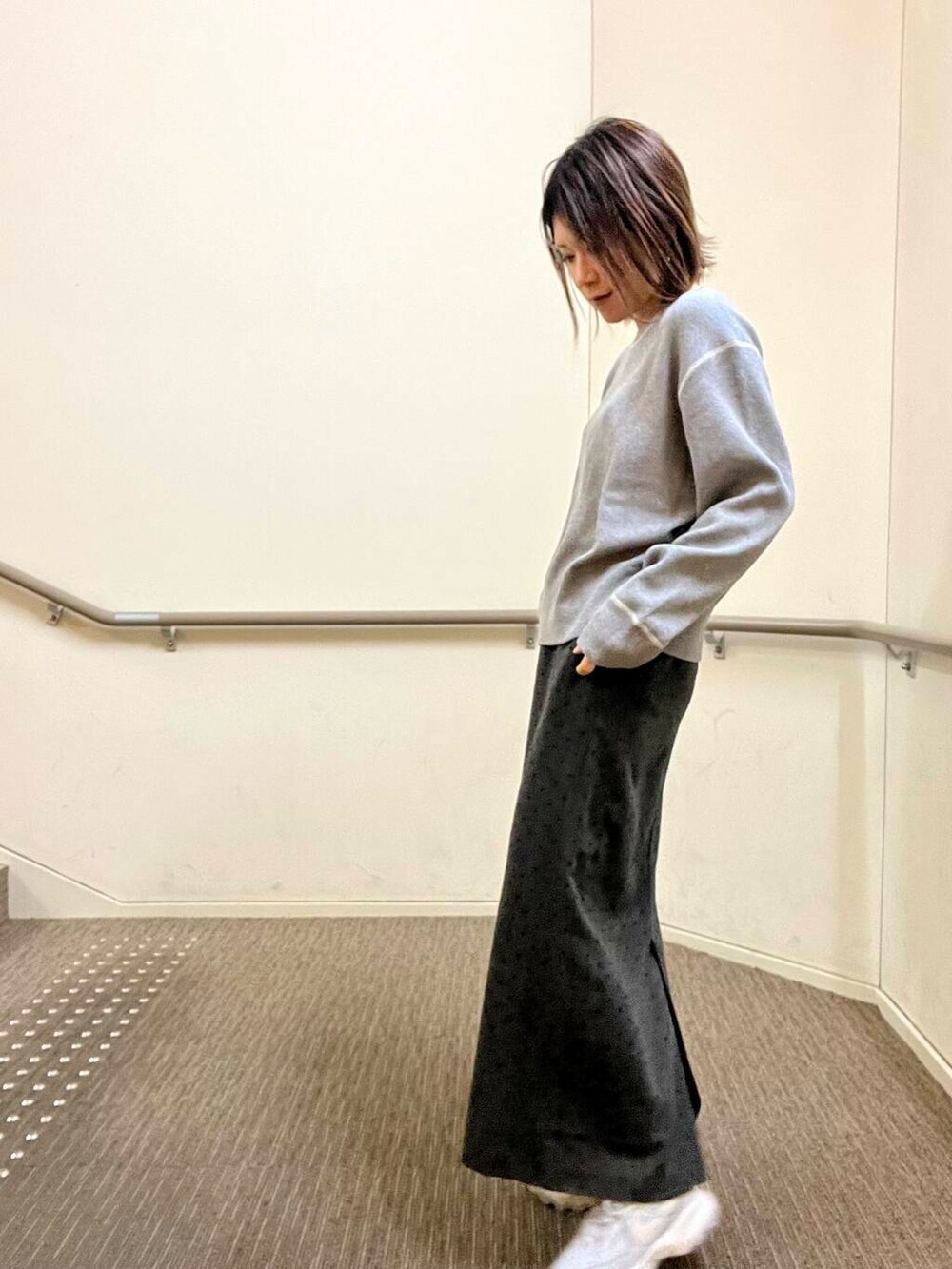 グレー系のスニーカー、グレー系のニット/セーター、グレー系のスカートを着用したレディースの冬コーディネートの7枚目の写真