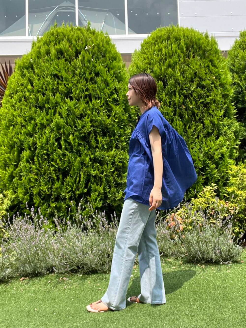 ブルー系のデニムパンツ、イエロー系のトートバッグ、ブラウン系のサンダルを着用したレディースの夏コーディネートの3枚目の写真