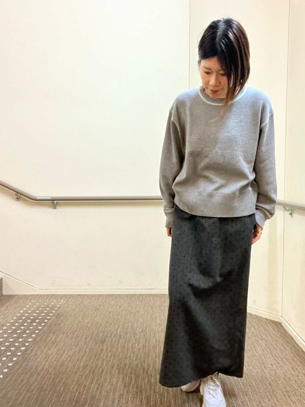 グレー系のスニーカー、グレー系のニット/セーター、グレー系のスカートを着用したレディースの冬コーディネートの6枚目の写真