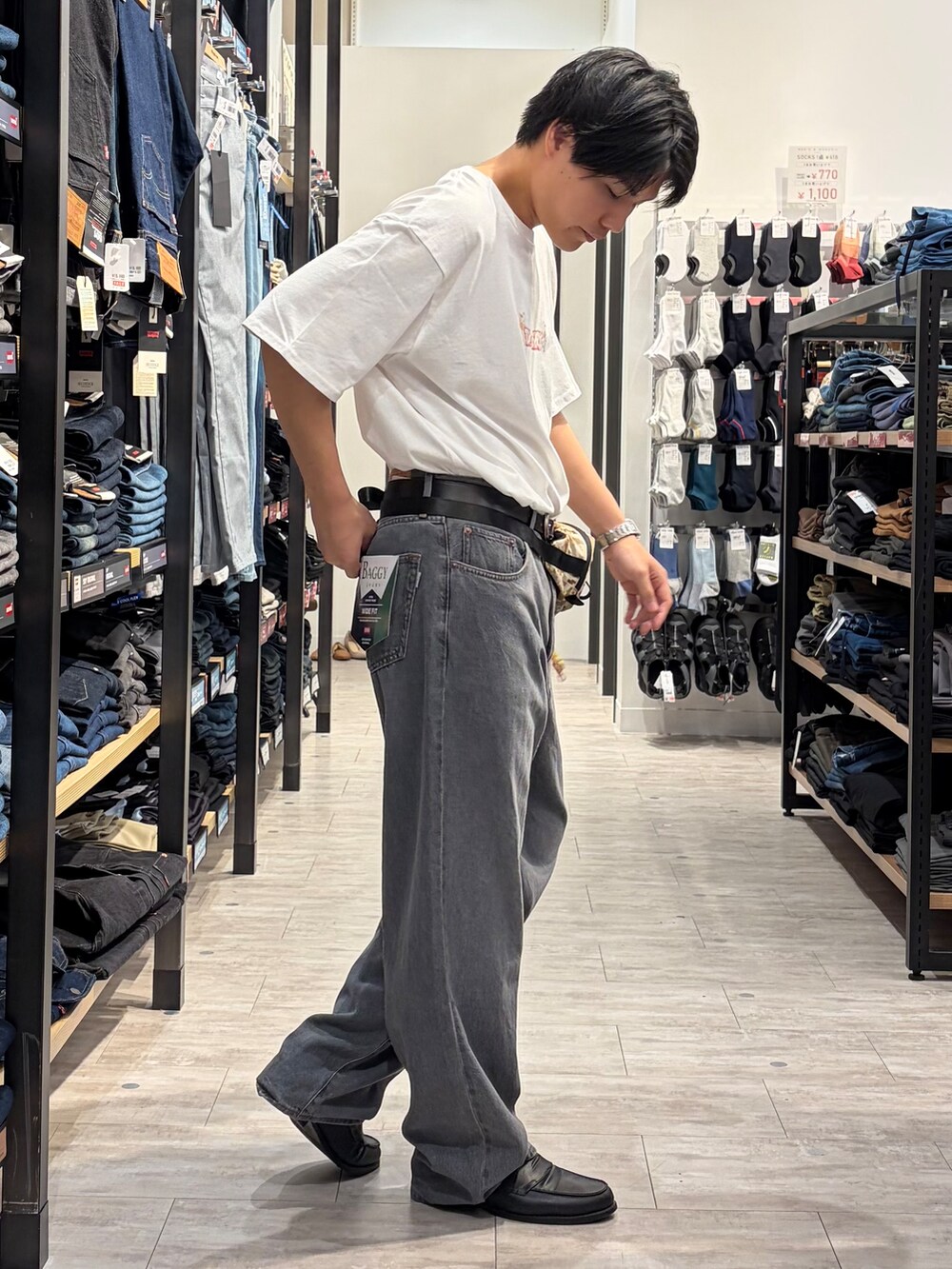 ブラック系のデニムパンツ、ホワイト系のTシャツ/カットソー、ベージュ系のボディバッグ/ウエストポーチを着用したメンズの夏コーディネートの4枚目の写真