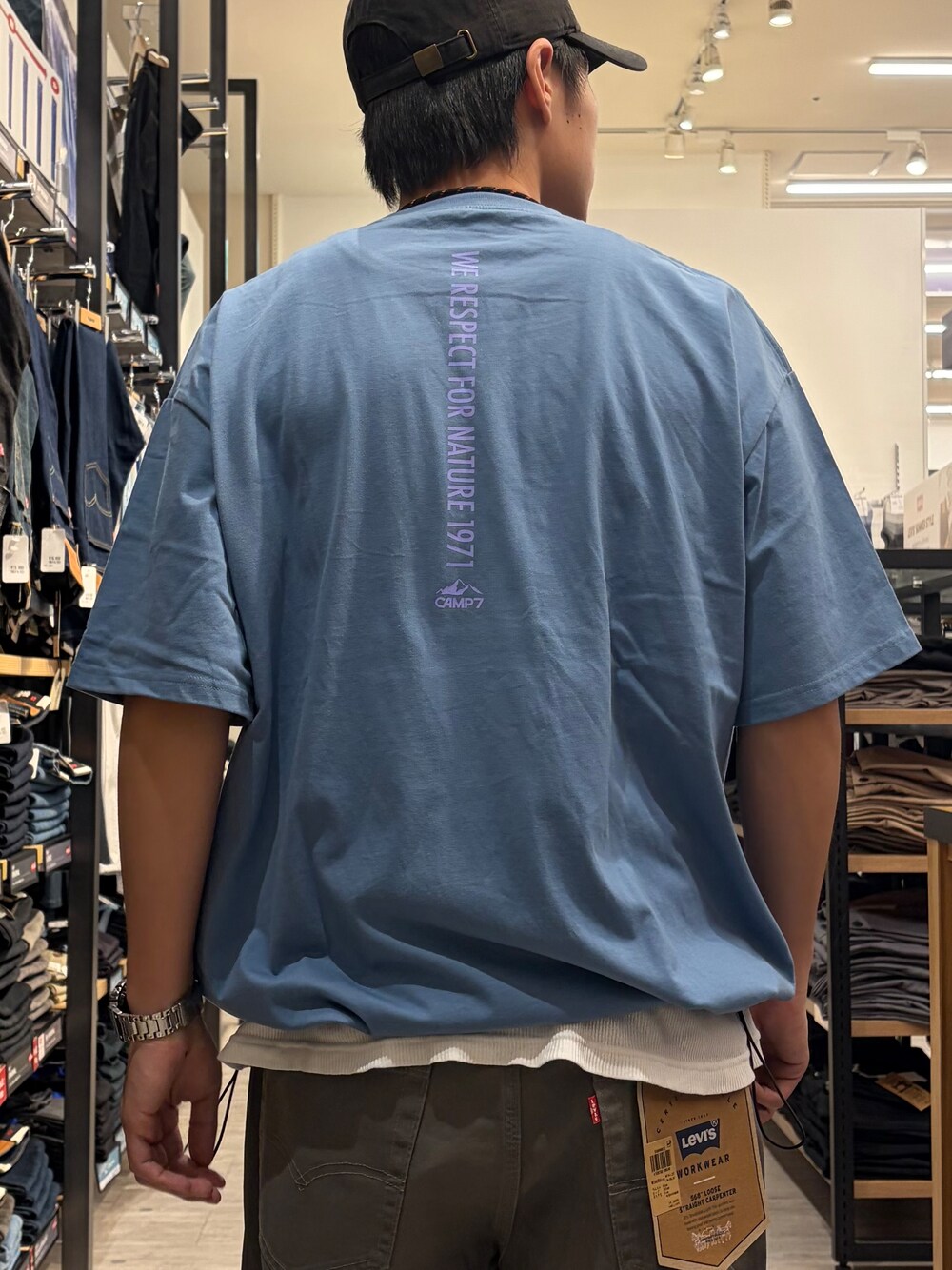 ブルー系のTシャツ/カットソー、グリーン系のデニムパンツ、ブラック系のショルダーバッグを着用したメンズの夏コーディネートの6枚目の写真