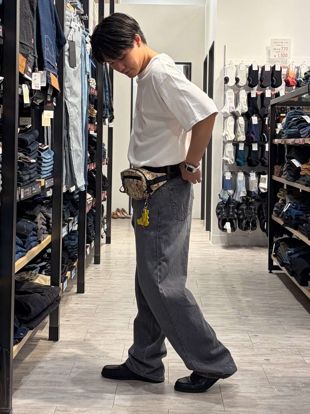 ブラック系のデニムパンツ、ホワイト系のTシャツ/カットソー、ベージュ系のボディバッグ/ウエストポーチを着用したメンズの夏コーディネートの3枚目の写真
