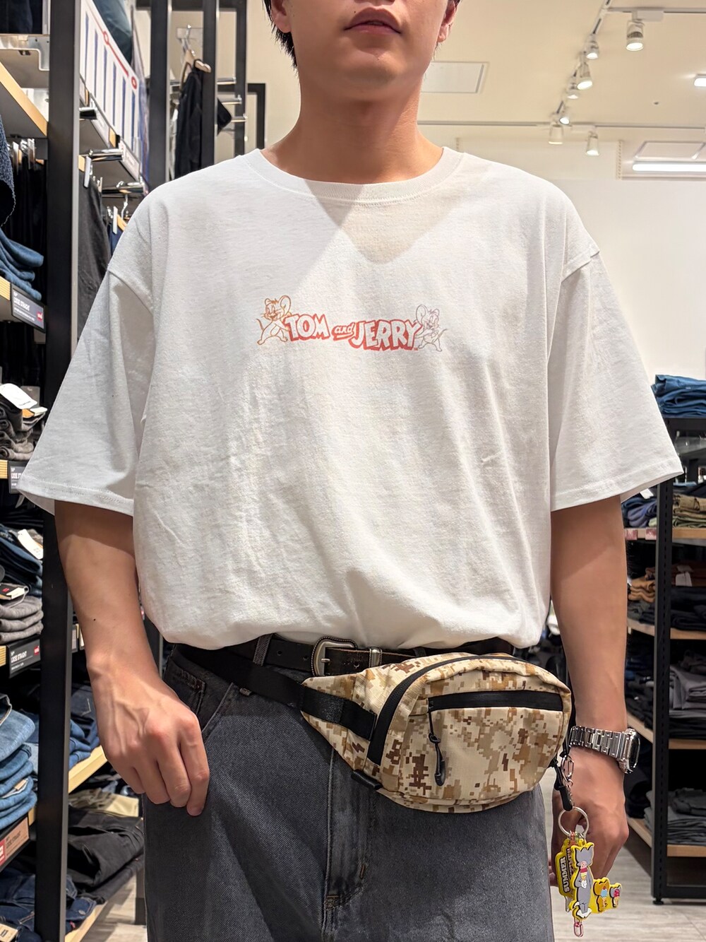ブラック系のデニムパンツ、ホワイト系のTシャツ/カットソー、ベージュ系のボディバッグ/ウエストポーチを着用したメンズの夏コーディネートの5枚目の写真