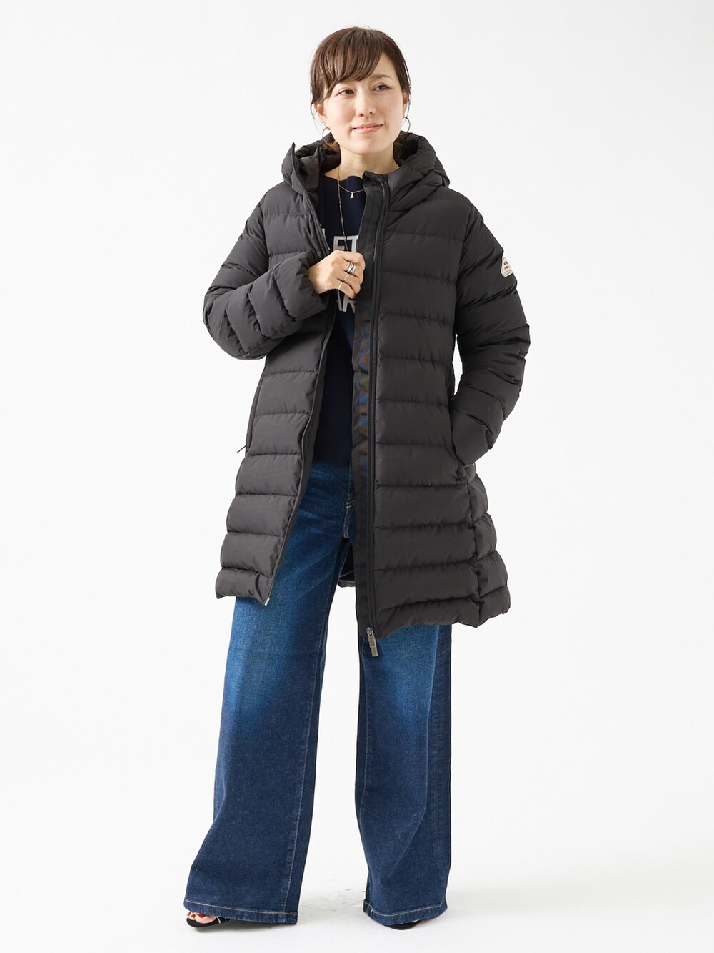 ブラック系のダウンジャケット/コート、ブルー系のニット/セーター、ブルー系のデニムパンツを着用したレディースの夏コーディネートの2枚目の写真