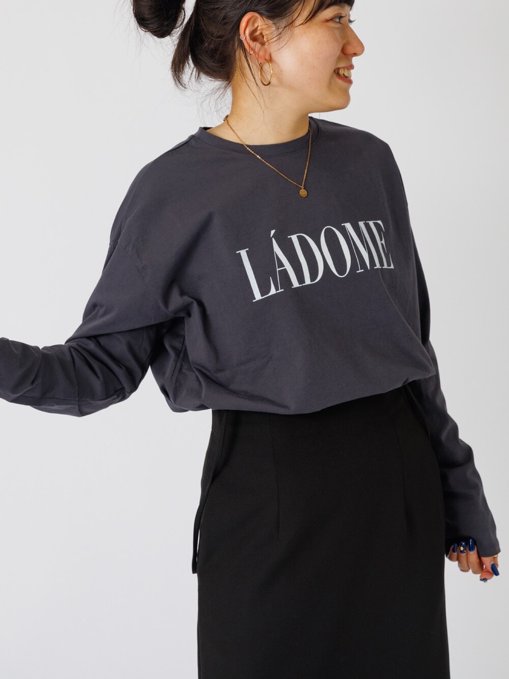 ブラック系のスカート、ホワイト系のスニーカー、ベージュ系のTシャツ/カットソーを着用したレディースの秋コーディネートの2枚目の写真