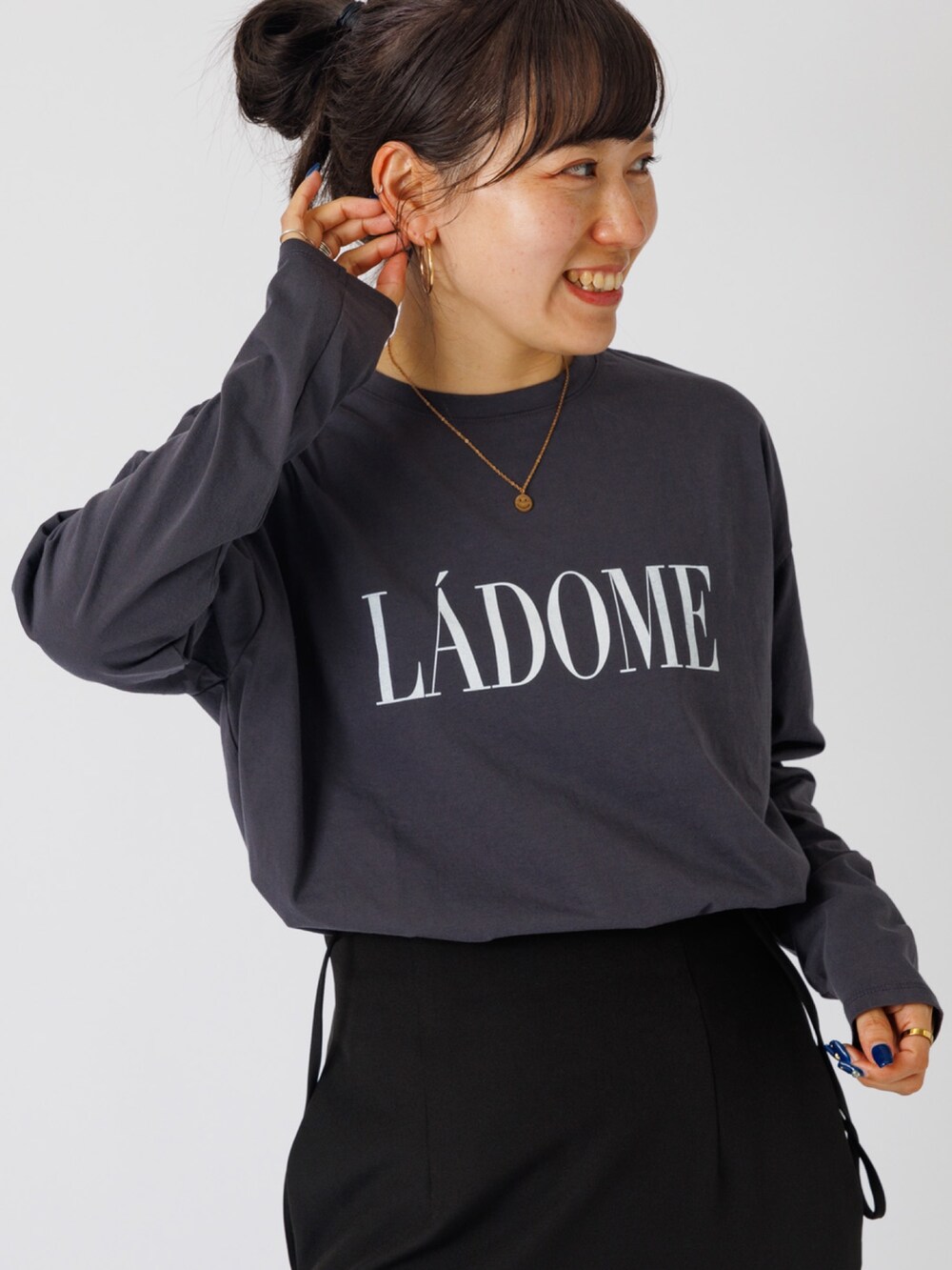 ブラック系のスカート、ホワイト系のスニーカー、ベージュ系のTシャツ/カットソーを着用したレディースの秋コーディネートの3枚目の写真