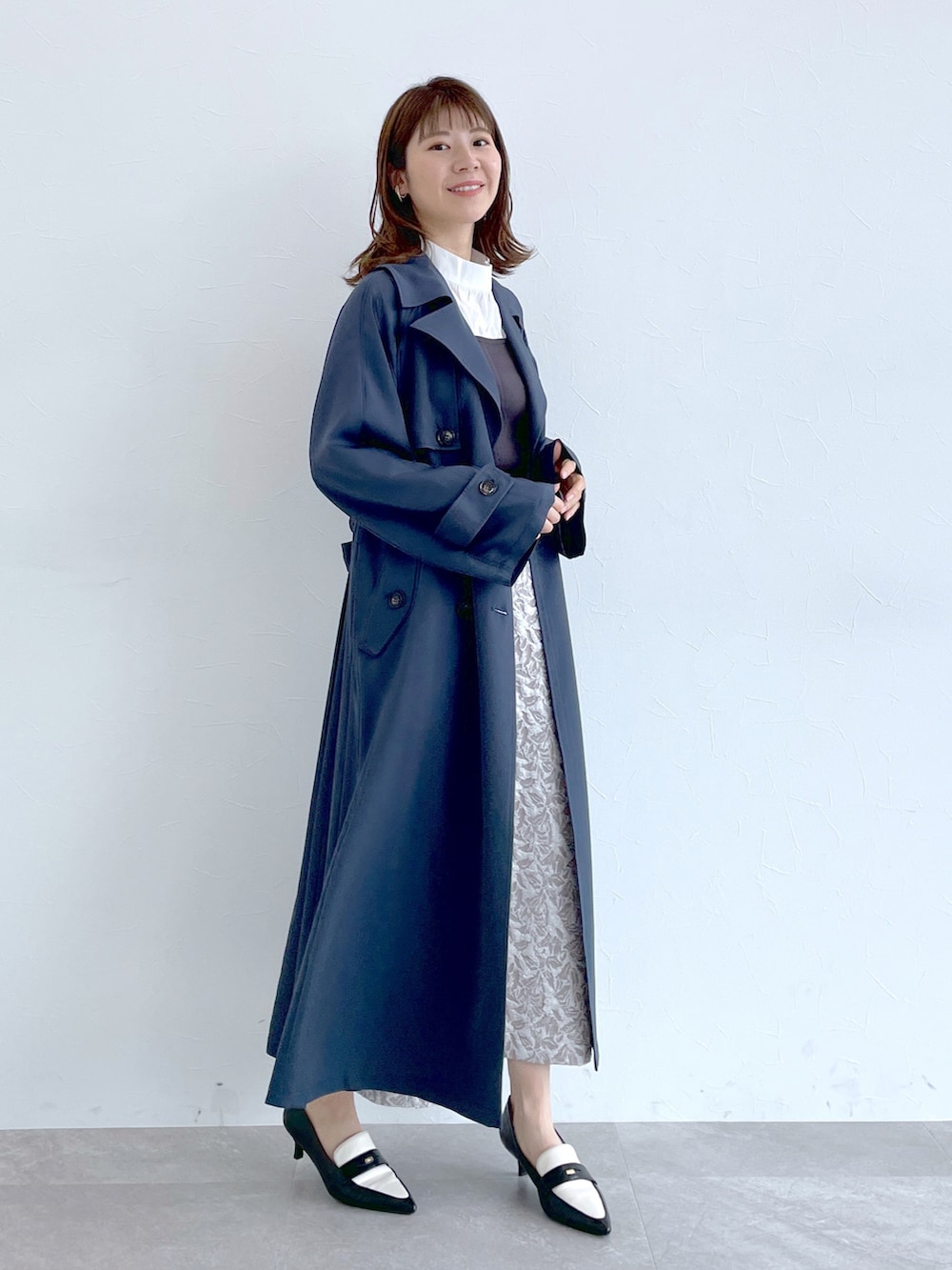 ブルー系のトレンチコート、グレー系のニット/セーター、グレー系のスカートを着用したレディースの冬コーディネートの5枚目の写真