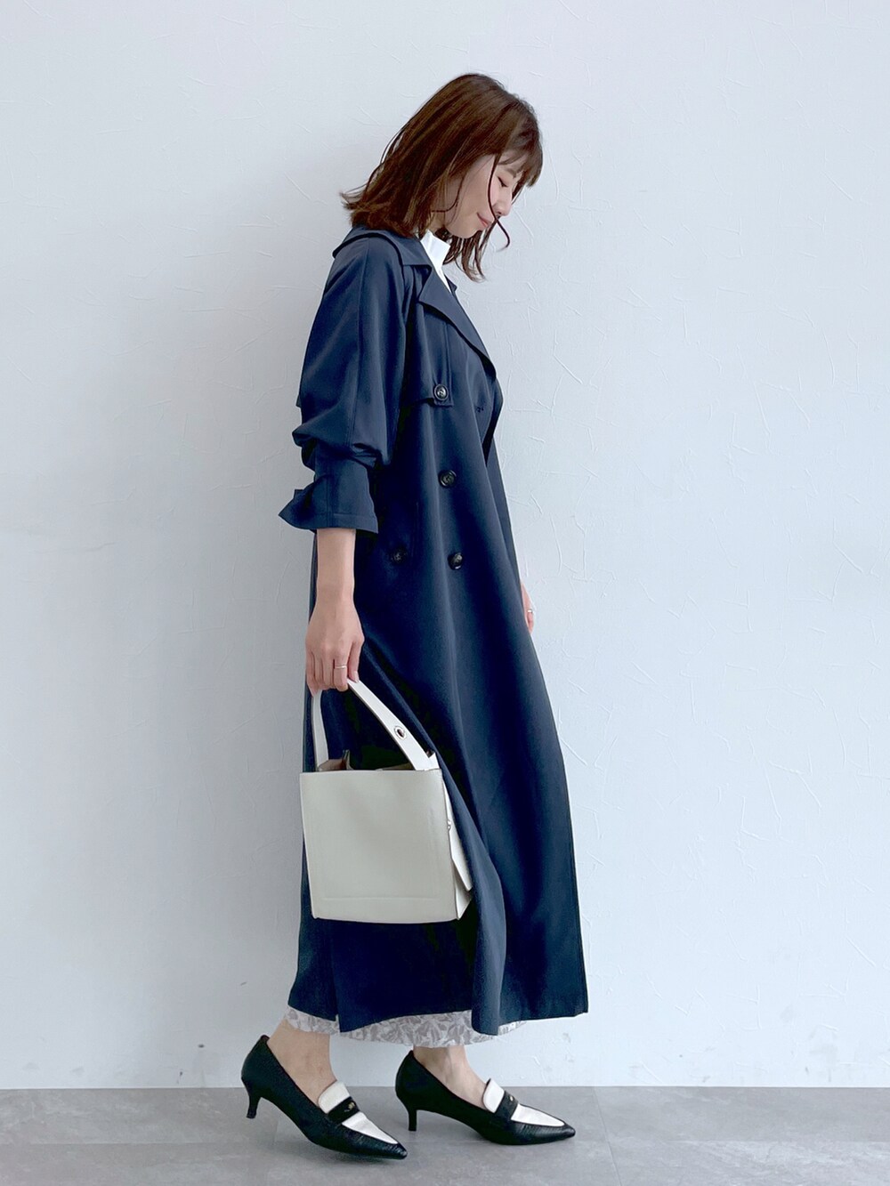 ブルー系のトレンチコート、グレー系のニット/セーター、グレー系のスカートを着用したレディースの冬コーディネートの3枚目の写真