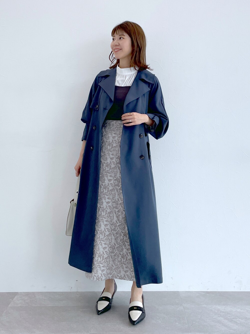 ブルー系のトレンチコート、グレー系のニット/セーター、グレー系のスカートを着用したレディースの冬コーディネートの2枚目の写真