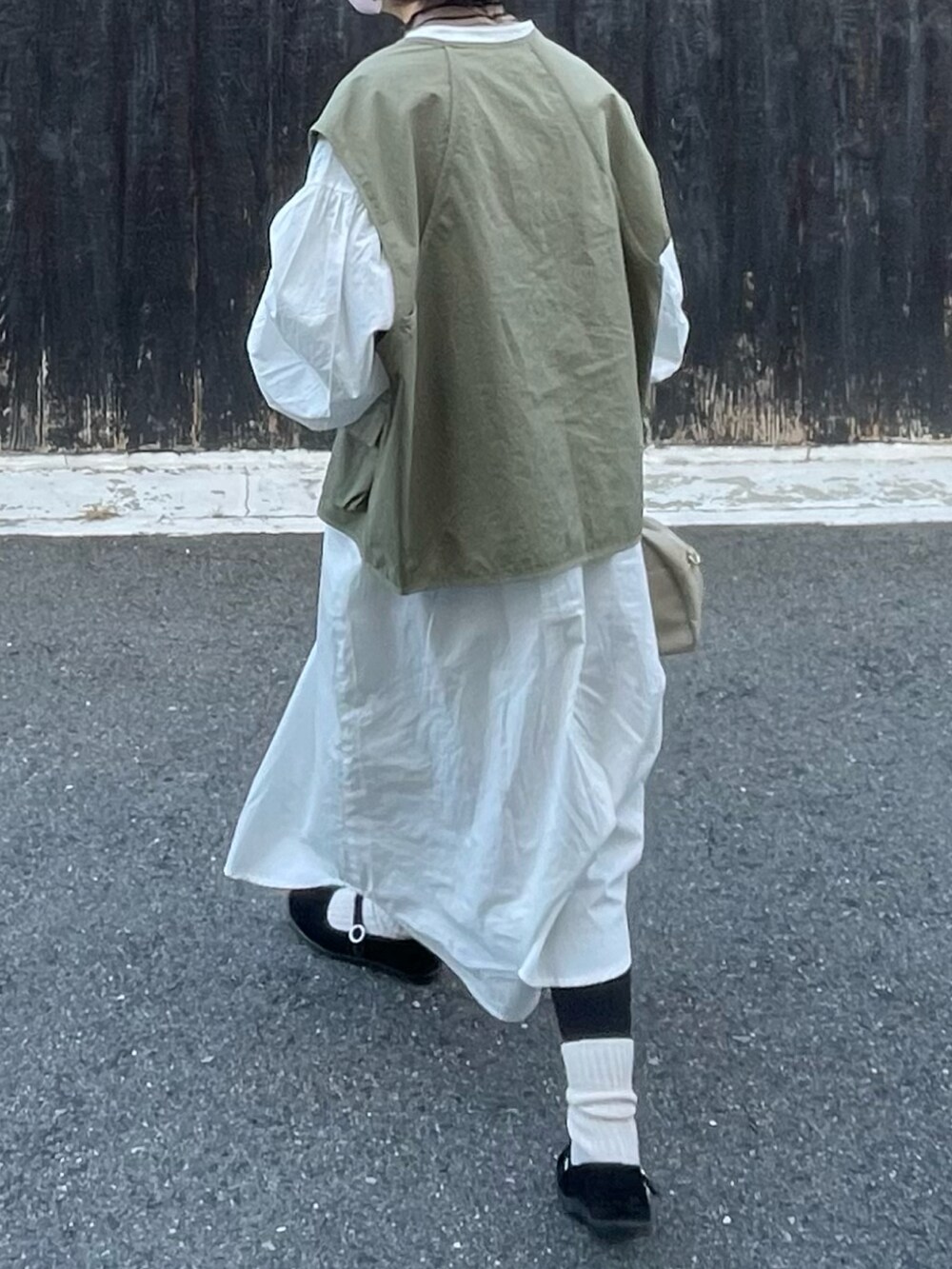 ホワイト系のシャツワンピース、ブラック系のバレエシューズ、グリーン系のベストを着用したレディースの秋コーディネートの3枚目の写真