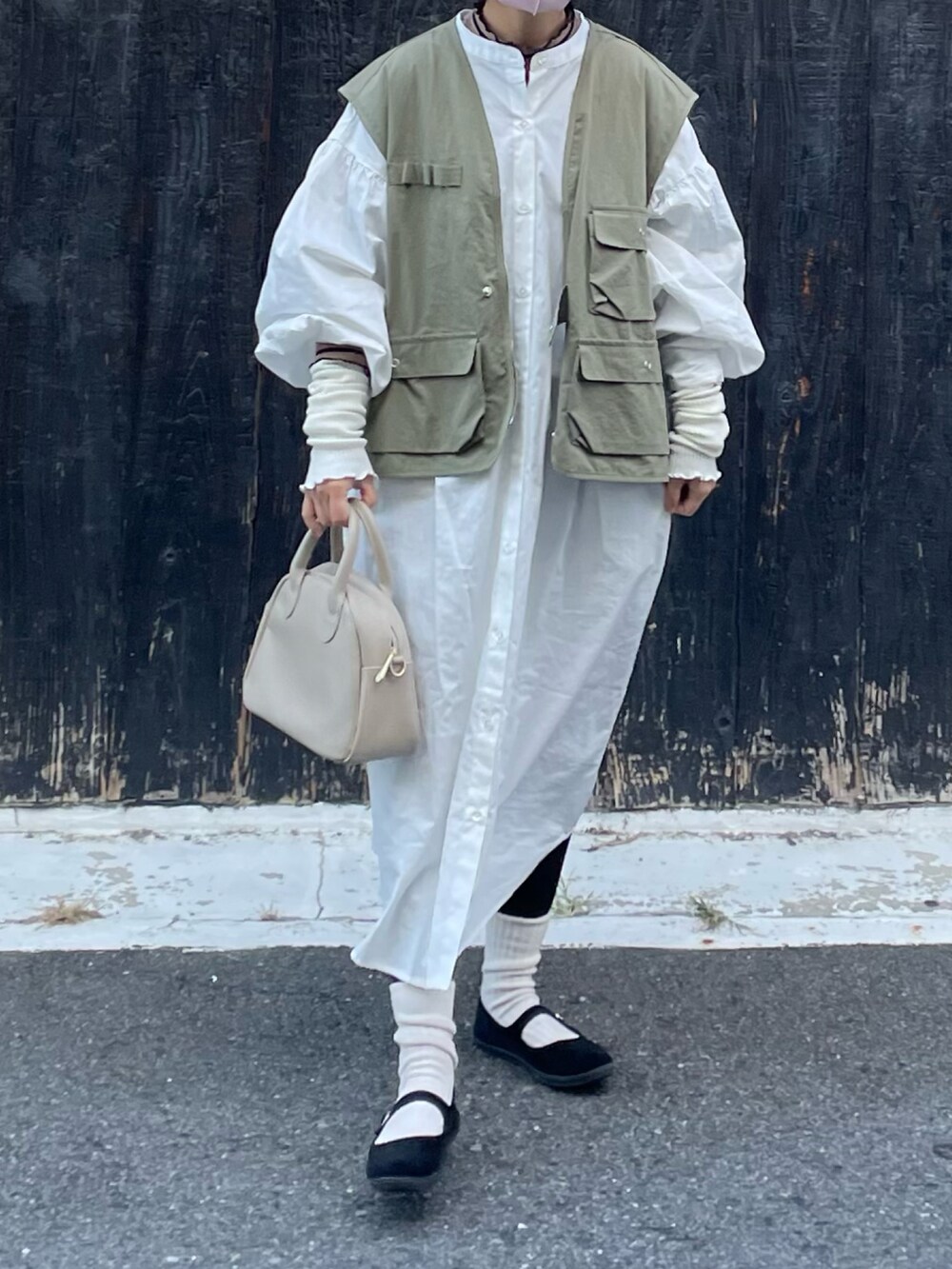 ホワイト系のシャツワンピース、ブラック系のバレエシューズ、グリーン系のベストを着用したレディースの秋コーディネートの2枚目の写真