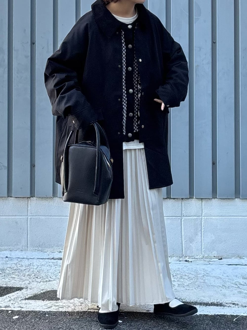 ブラック系のその他アウター、ブラック系のカーディガン/ボレロ、ベージュ系のスカートを着用したレディースの冬コーディネートの2枚目の写真