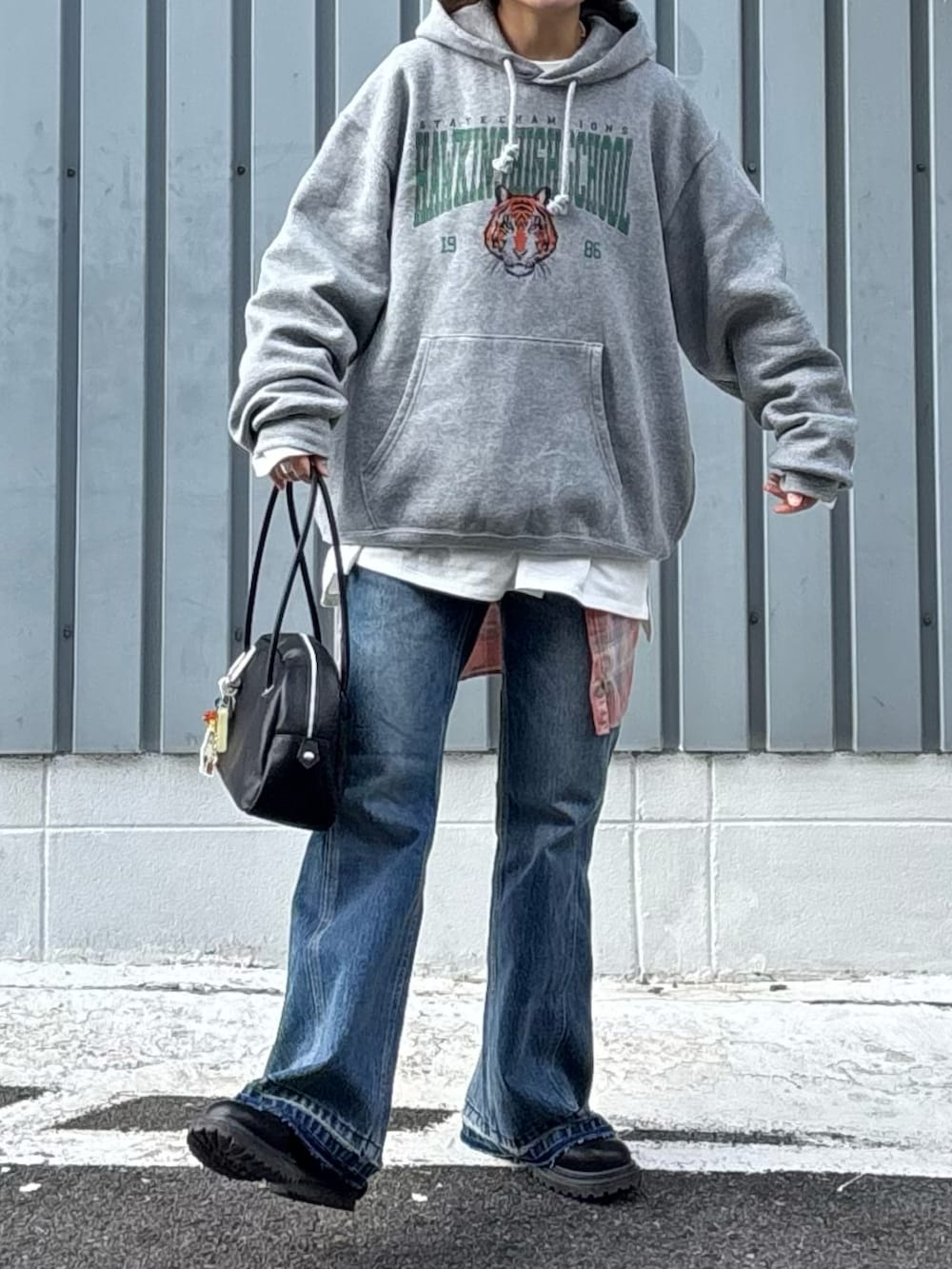 グレー系のパーカー、ブラック系のブーツ、ブルー系のデニムパンツを着用したレディースの冬コーディネートの2枚目の写真