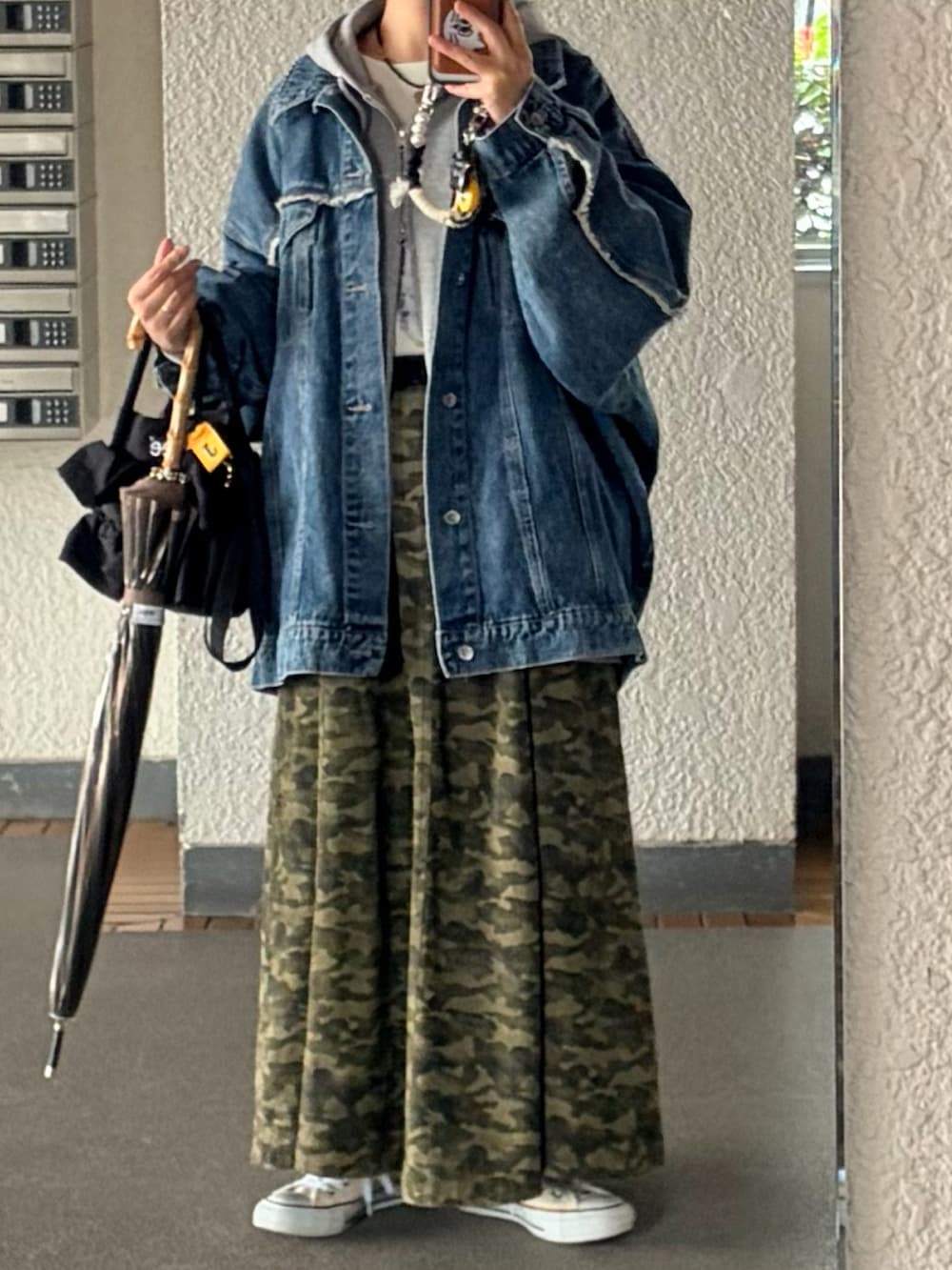 グレー系のスカート、グレー系のパーカー、ブラック系のショルダーバッグを着用したレディースの春コーディネートの2枚目の写真