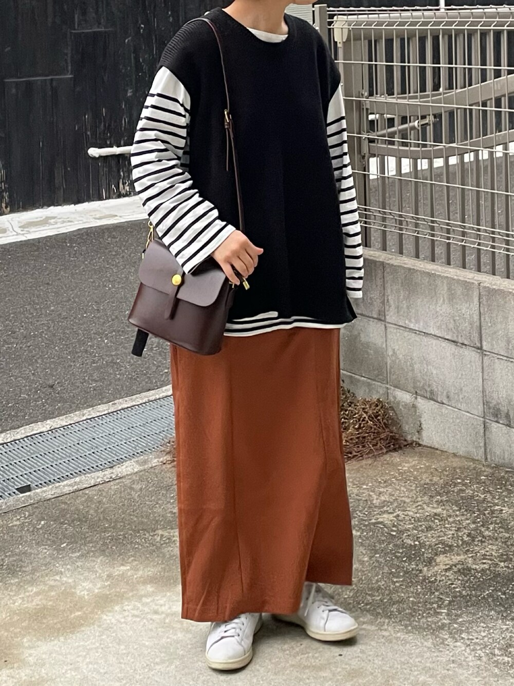 オレンジ系のスカート、ホワイト系のスニーカー、ブラウン系のショルダーバッグを着用したレディースの冬コーディネートの2枚目の写真
