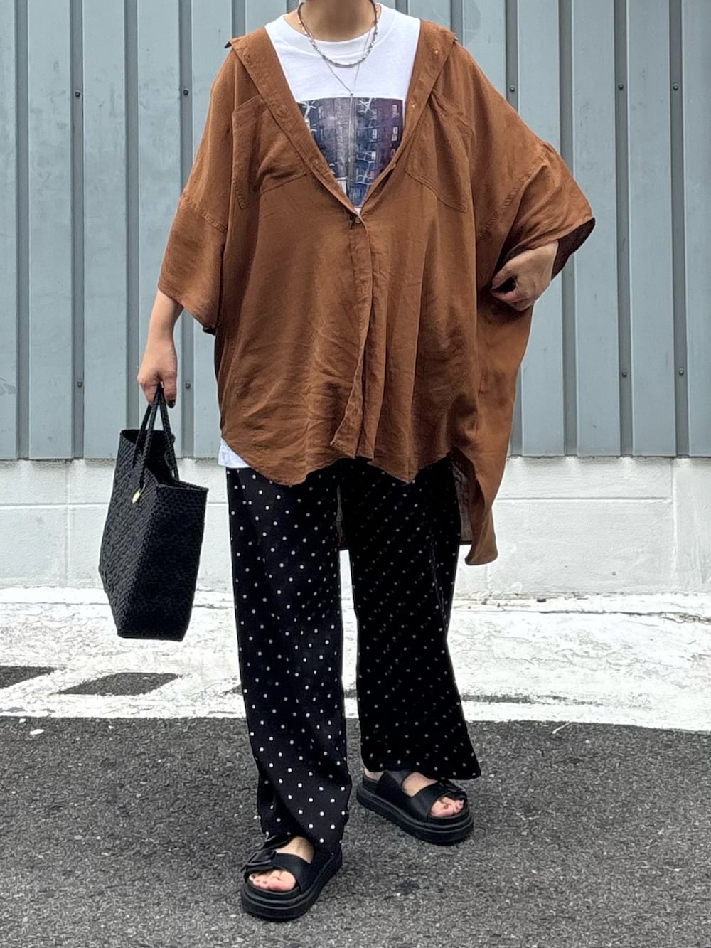 ブラック系のかごバッグ、ブラック系のサンダル、ブラウン系のシャツ/ブラウスを着用したレディースの秋コーディネートの2枚目の写真