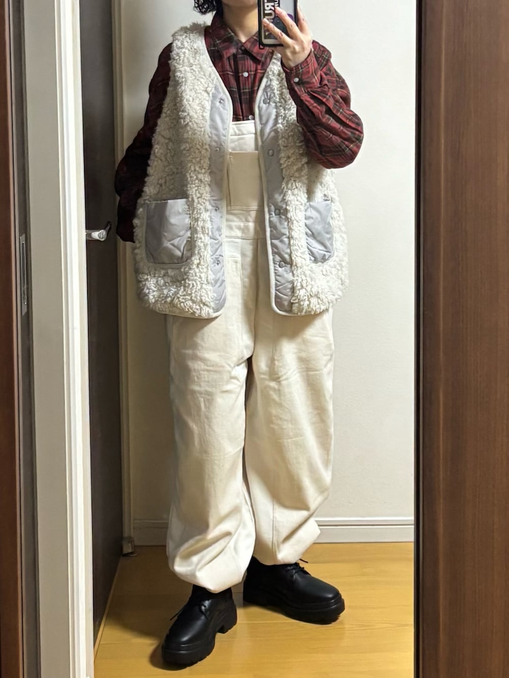 ホワイト系のオールインワン・サロペット、ベージュ系のベスト、レッド系のシャツ/ブラウスを着用したレディースの冬コーディネートの2枚目の写真