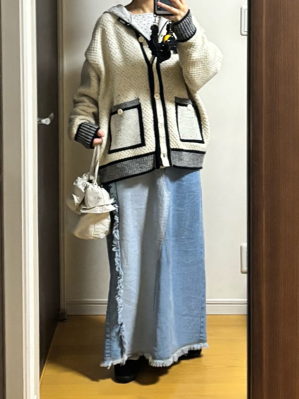 ブルー系のデニムスカート、ホワイト系のカーディガン/ボレロを着用したレディースの冬コーディネートの2枚目の写真