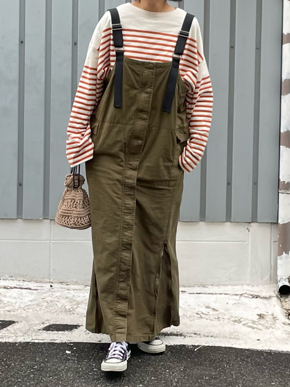 イエロー系のTシャツ/カットソー、ブラック系のスニーカー、グリーン系のジャンパースカートを着用したレディースの春コーディネートの2枚目の写真