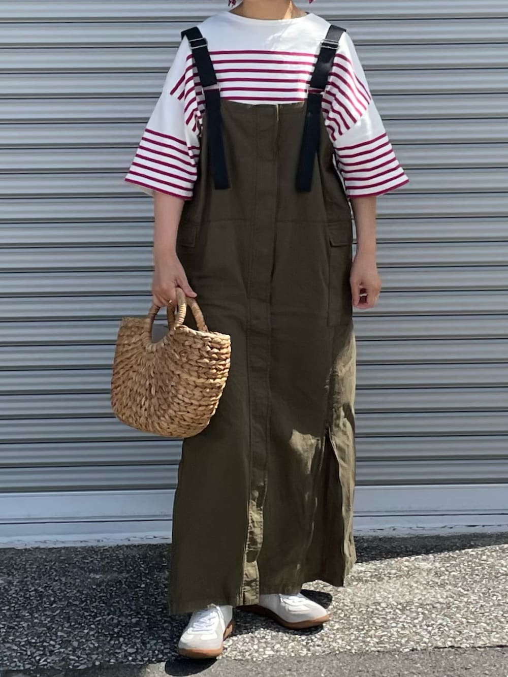 ホワイト系のスニーカー、ベージュ系のかごバッグ、グリーン系のジャンパースカートを着用したレディースの夏コーディネートの2枚目の写真