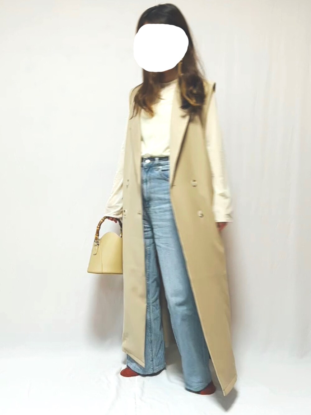 ブルー系のデニムパンツ、ベージュ系のハンドバッグ、ベージュ系のTシャツ/カットソーを着用したレディースの春コーディネートの2枚目の写真