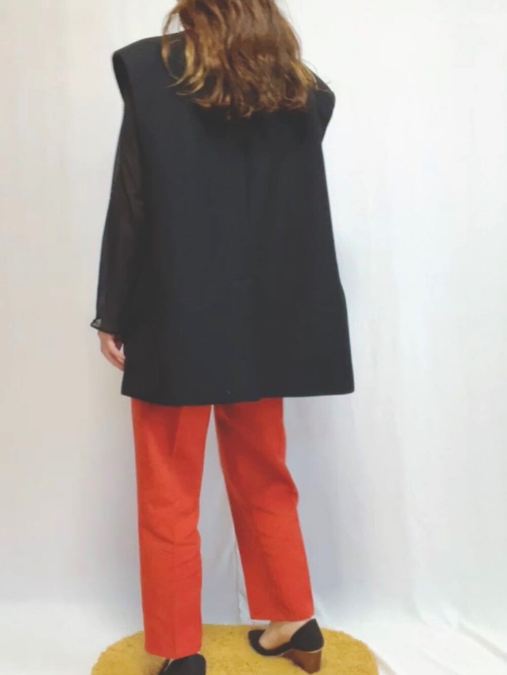 ブラック系のパンプス、オレンジ系のスラックス、ブラック系のジャケット/アウターを着用したレディースの春コーディネートの2枚目の写真