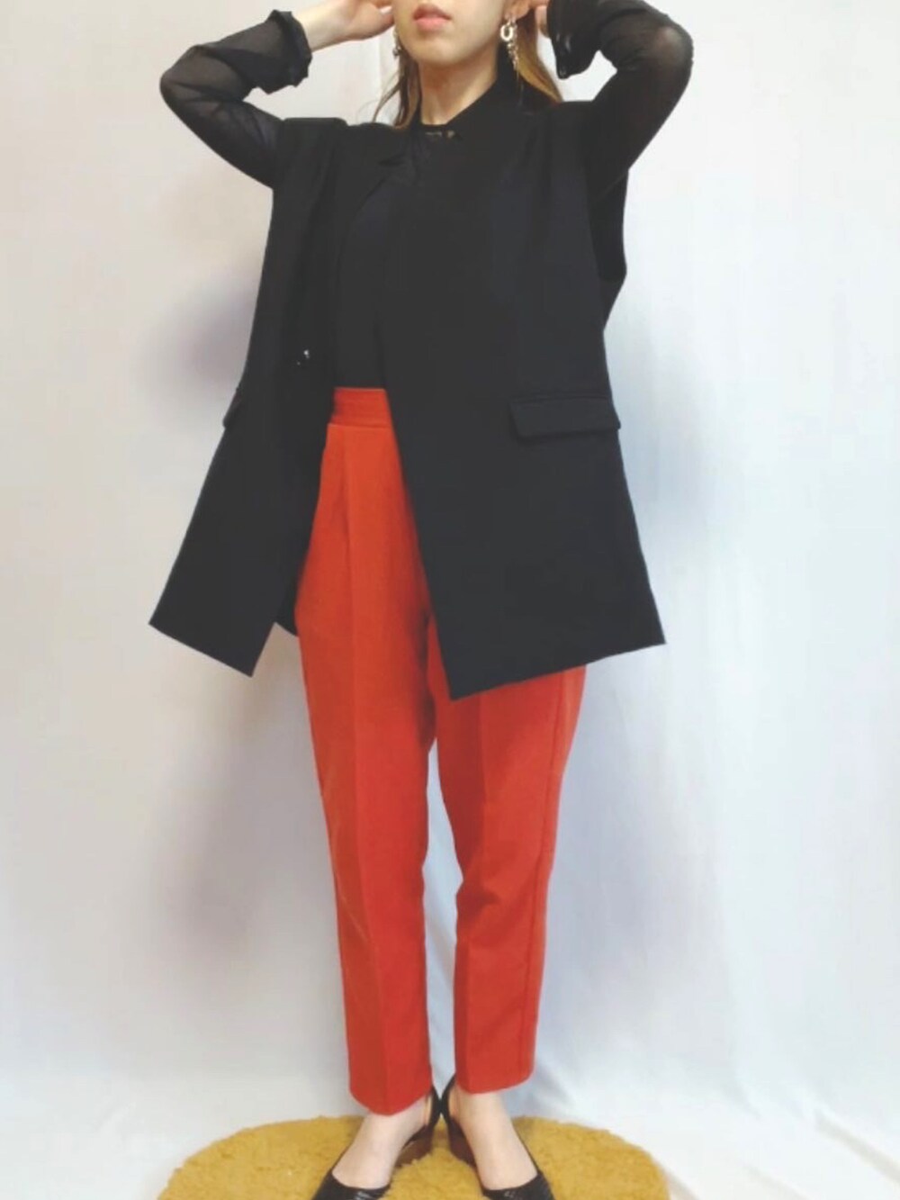 ブラック系のパンプス、オレンジ系のスラックス、ブラック系のジャケット/アウターを着用したレディースの春コーディネートの3枚目の写真