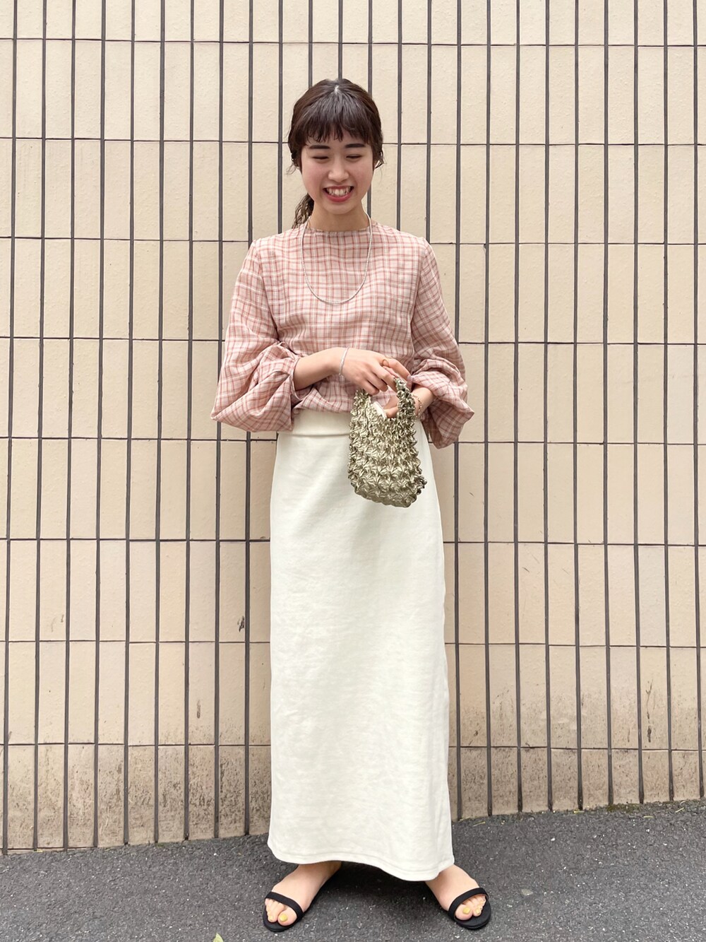 ブラック系のサンダル、オレンジ系のシャツ/ブラウス、ホワイト系のスカートを着用したレディースの春コーディネートの2枚目の写真