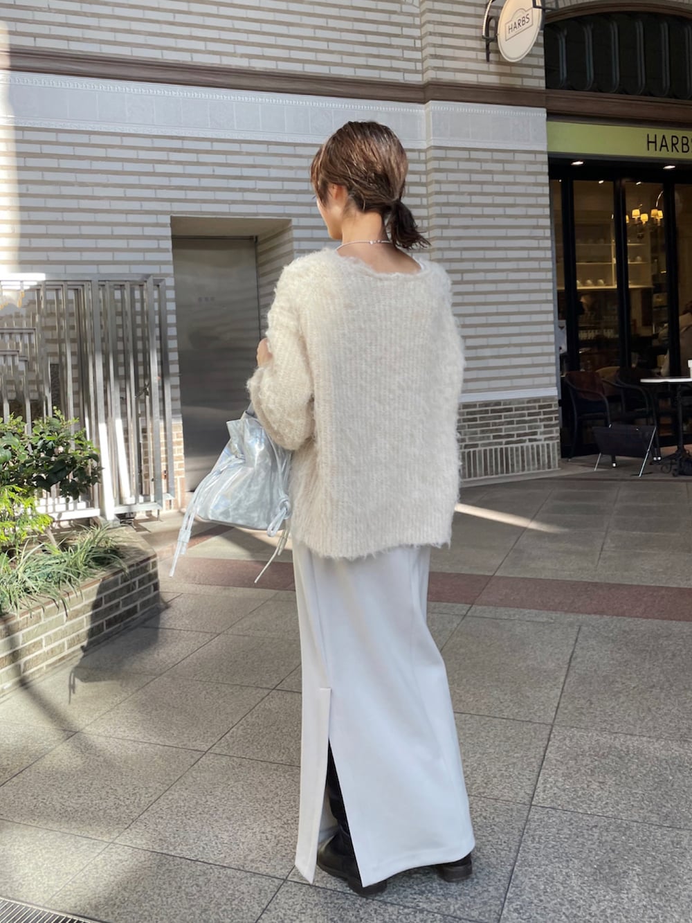 シルバー系のショルダーバッグ、グレー系のスカート、ブラウン系のブーツを着用したレディースの冬コーディネートの5枚目の写真
