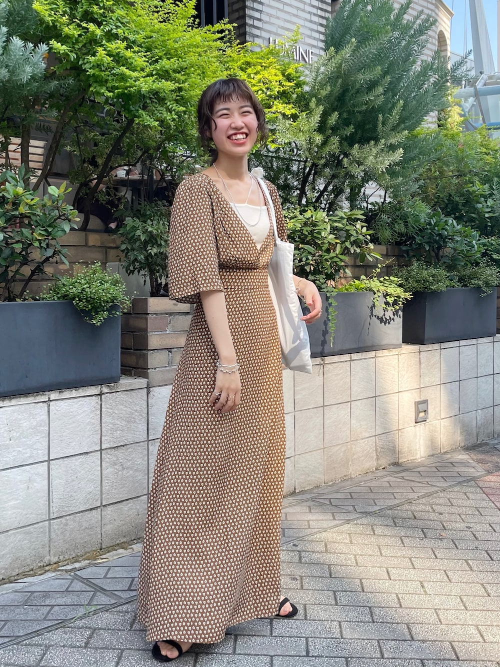 ブラウン系のワンピース、ブラック系のサンダル、ホワイト系のトートバッグを着用したレディースの夏コーディネートの5枚目の写真